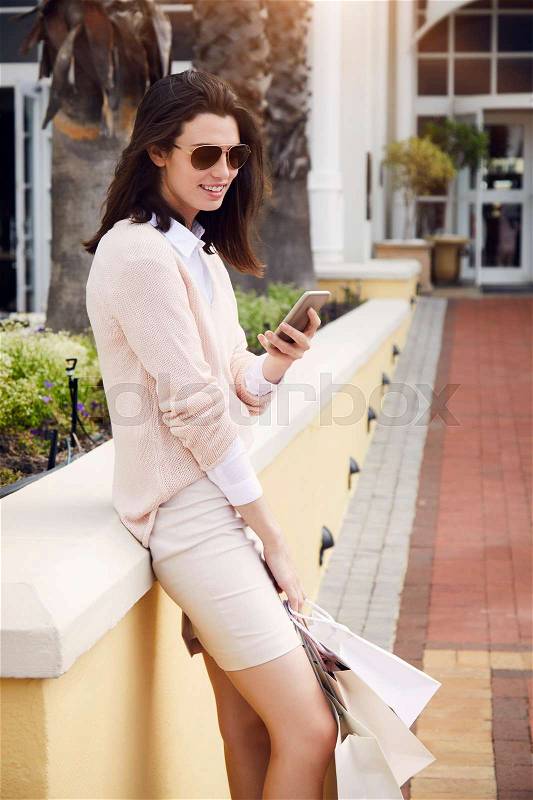 City girl on phone with shopping bags, smiling, stock photo