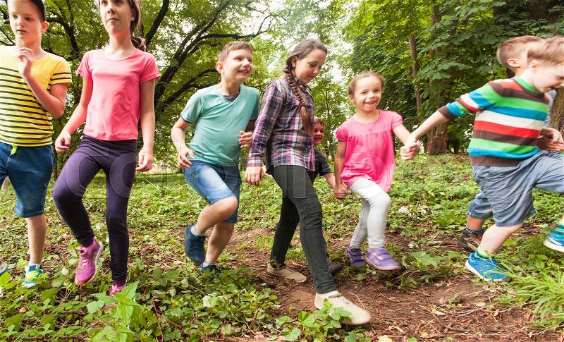 Group of happy children running across the lawn in summer, stock photo