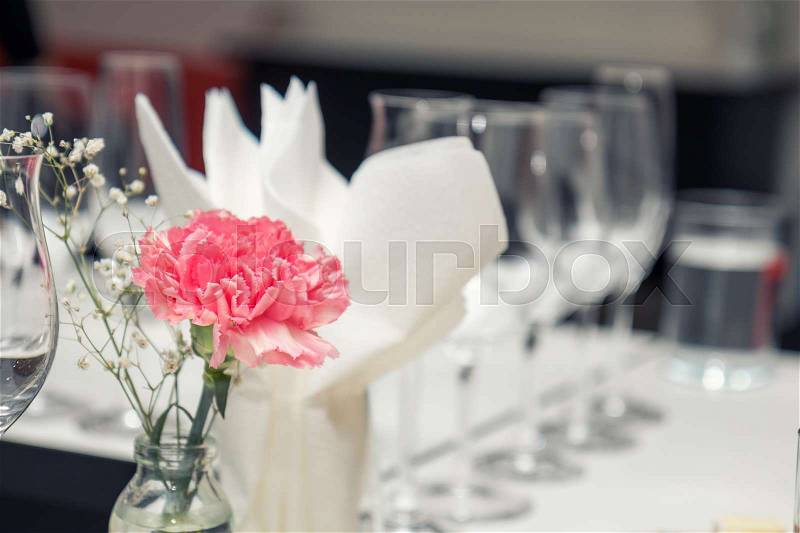 Close up picture of wine glasses with flower and empty glasses in restaurant. Serving table prepared for event party or wedding. Soft focus, selective focus. Toned, stock photo
