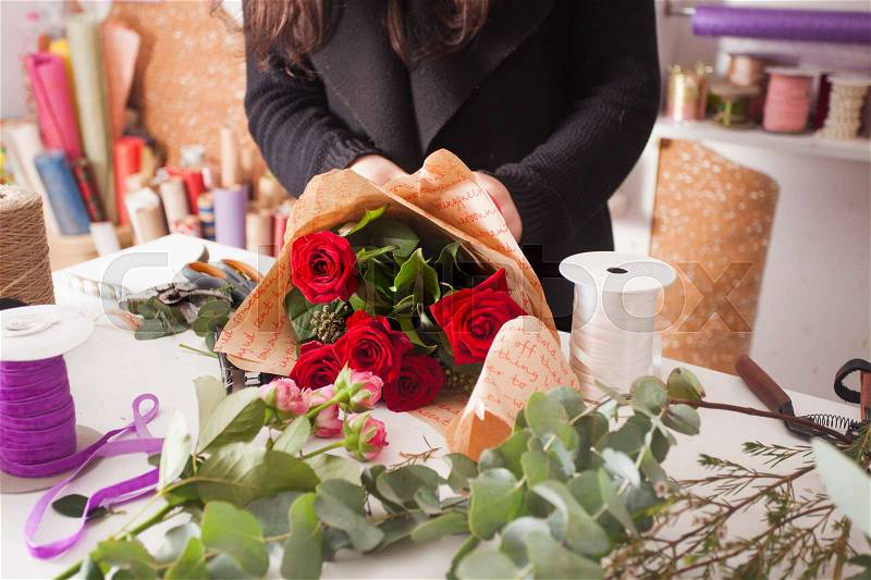 Florist making fashion bouquet of beautiful red roses, stock photo