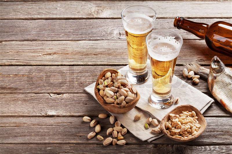 Lager beer glasses and snacks on wooden table. Nuts and dry fish. With copy space, stock photo