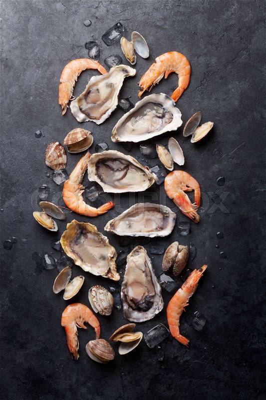 Fresh seafood on stone table. Oysters, prawns and scallops. Top view, stock photo