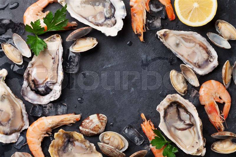 Fresh seafood on stone table. Oysters, prawns and scallops. Top view with copy space, stock photo