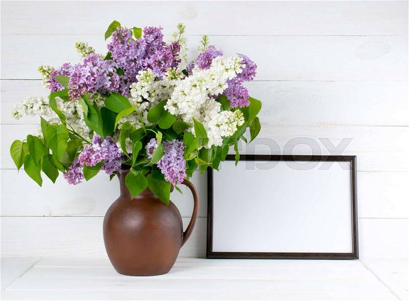 Lilac Bouquet in clay jug with motivational frame for your text or picture on background of white wooden planks in scandinavian style, stock photo