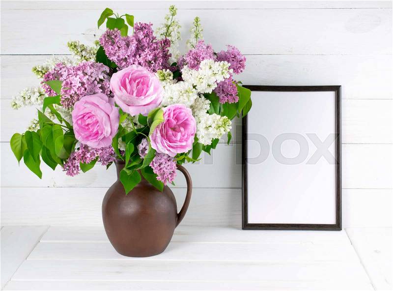 Lilac and roses in clay jug with motivational frame for your text or picture on background of white wooden planks in scandinavian style, stock photo