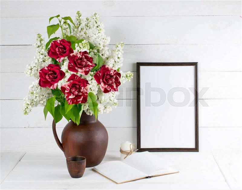 Lilac bouquet with roses in clay jug with motivational frame for your text or picture on background of white wooden planks in scandinavian style, stock photo