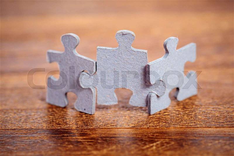 Three jigsaw puzzle pieces on a table joint together. Shallow depth of field, stock photo