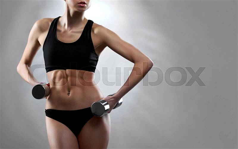 Sports motivation. Cropped studio shot of a gorgeous fit woman showing off her stunning sporty body and abs holding weights on grey background, stock photo