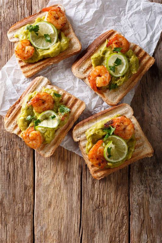 Delicious sandwiches with guacamole, shrimps and lime close-up on the table. Vertical view from above , stock photo