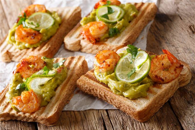 Delicious sandwiches with guacamole, shrimps and lime close-up on the table. horizontal , stock photo