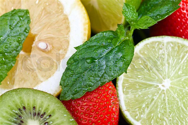 Ripe juicy lemon , lime , kiwi , strawberry and peppermint with water drops . Fresh healthy fruits and berries , stock photo