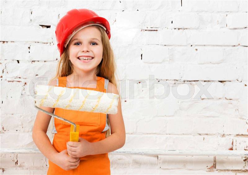 Little girl-worker in orange uniform with paint roller in hands, stock photo