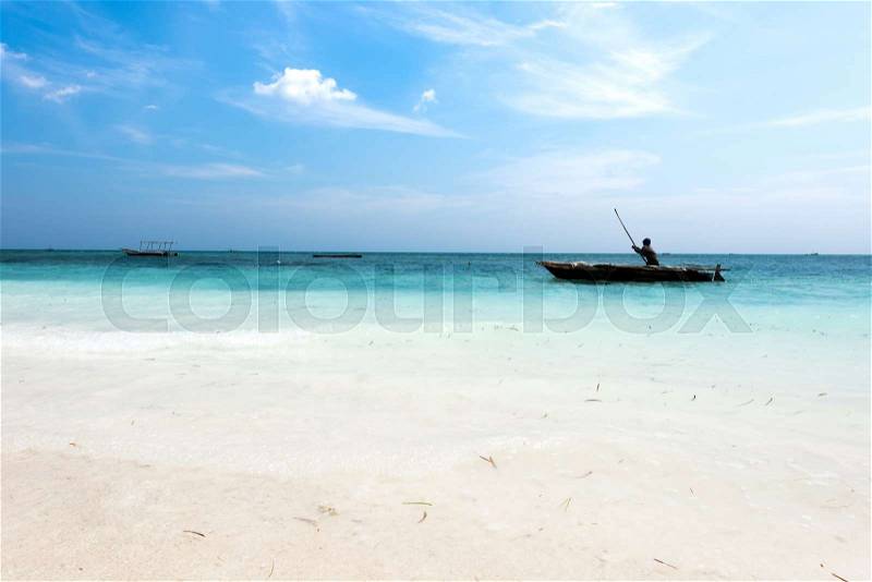 Landscape with man in a boat in ocean near African shore, stock photo