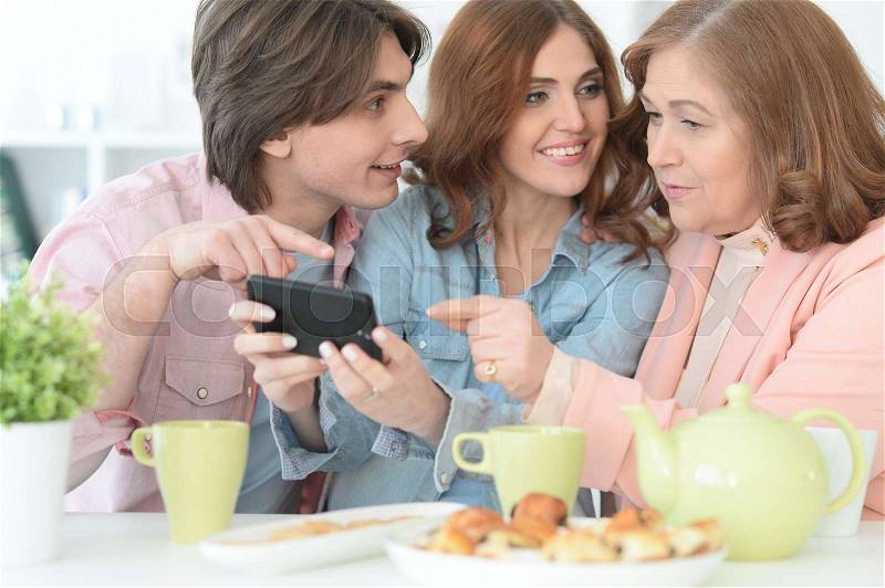 Portrait of happy family using mobile phone together, stock photo