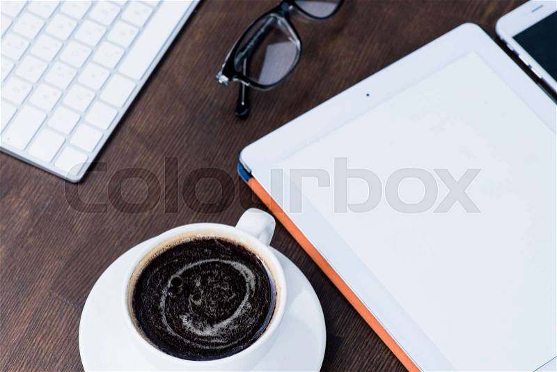 Close-up view of digital tablet and cup of coffee on office desk, stock photo