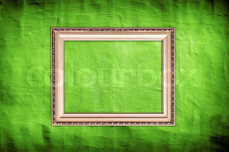 Vintage golden frame with copy-space hanging on grungy green wall, stock photo