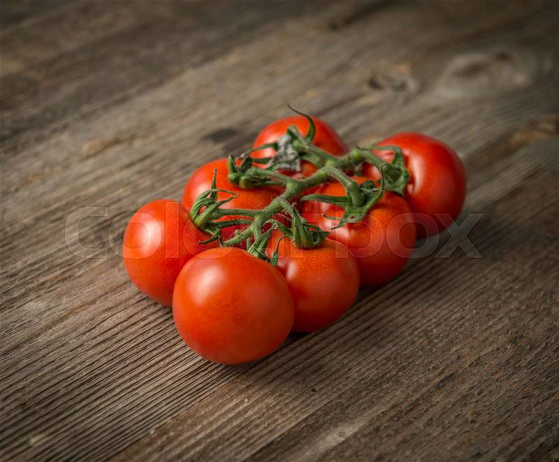 Red ripe fresh tomatoes connected to each other on the wooden table, closeup, stock photo