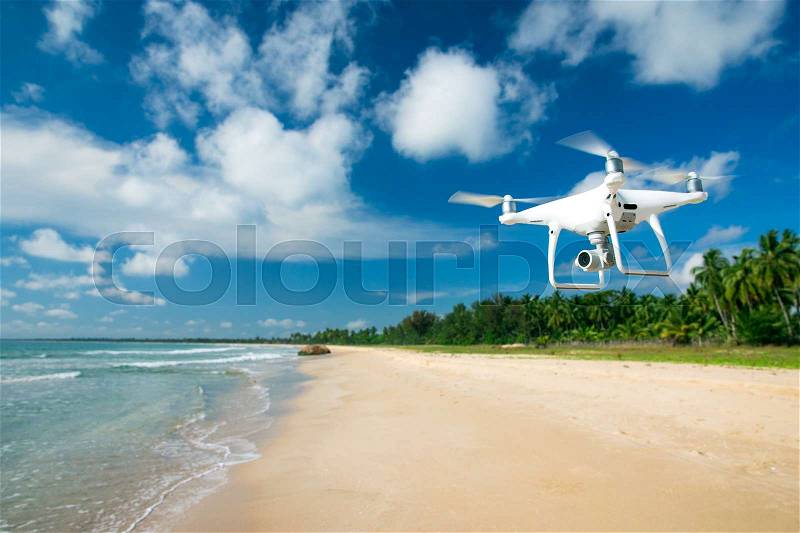 Drone flying over sea. white drone hovering in a bright blue sky. New technology in the aero photo shooting, stock photo