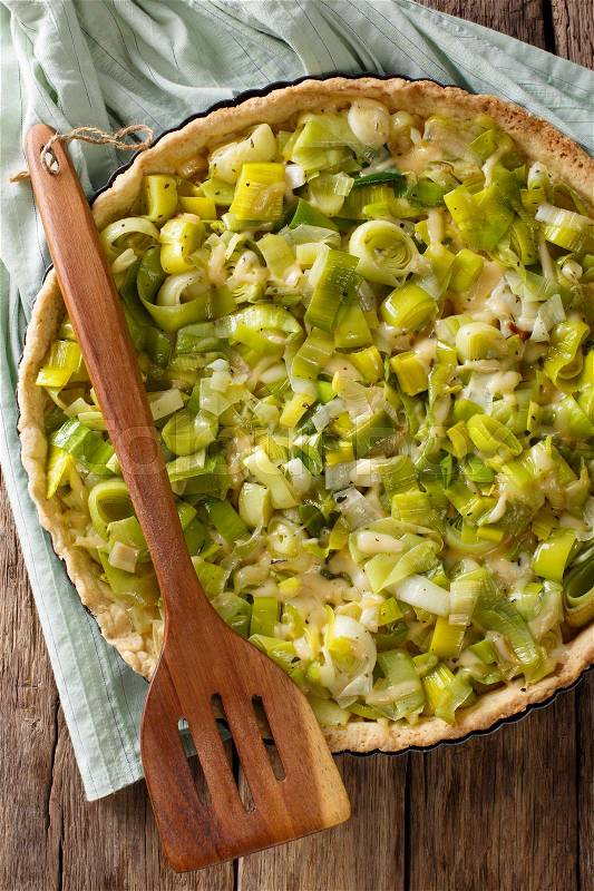 Homemade leek pie with cheese close up in baking dish on the table. Vertical view from above , stock photo