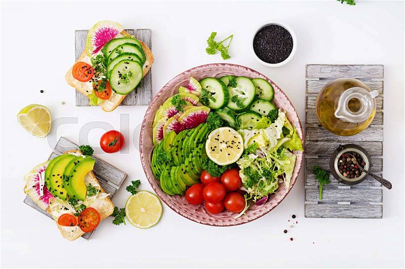 Diet menu. Healthy lifestyle. Vegan salad of fresh vegetables - tomatoes, cucumber, watermelon radish and avocado on plate and sandwiches with vegetables. Flat lay. Top view, stock photo