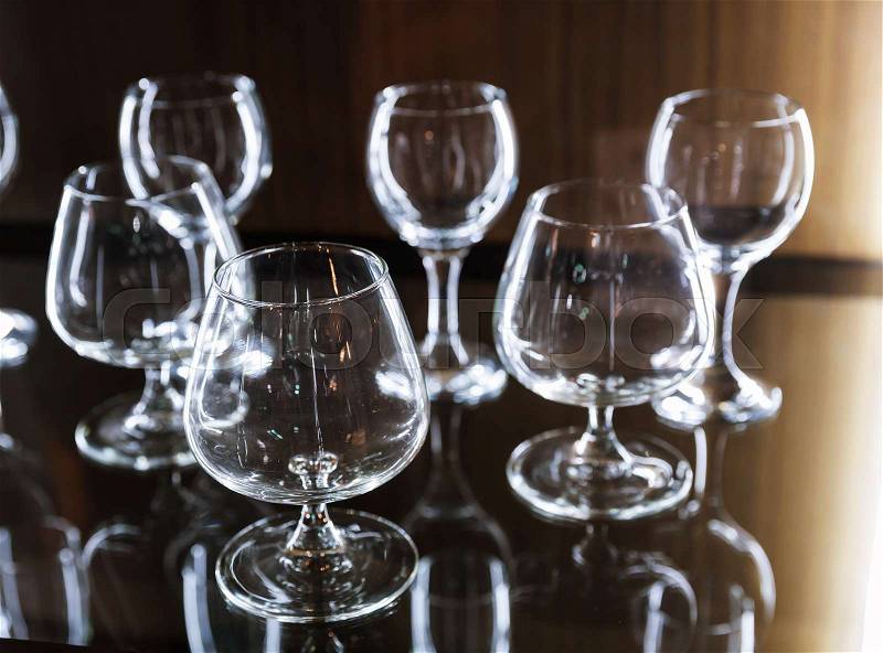 Clean alcohol glasses on wooden shelf, selective focus.Interior decoration for kitchen, restaurant or bar, stock photo