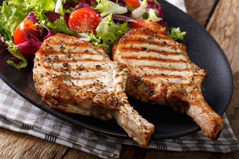 Barbecue spicy pork chop with fresh vegetable salad close-up on plate. horizontal , stock photo