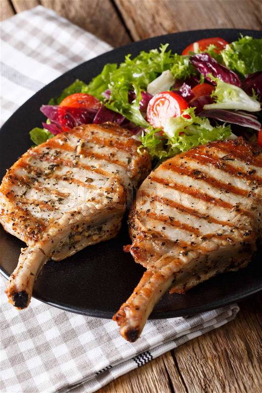 BBQ spicy pork cutlet with mixed salad on a plate close-up on the table. vertical , stock photo