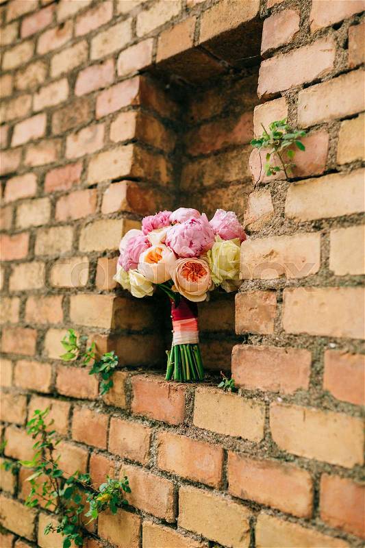 Bouquet of peonies on the background of the stone wall of red brick, stock photo