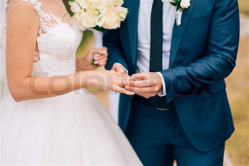 The groom dresses a ring on the finger of the bride at a wedding ceremony. Wedding in Montenegro, stock photo