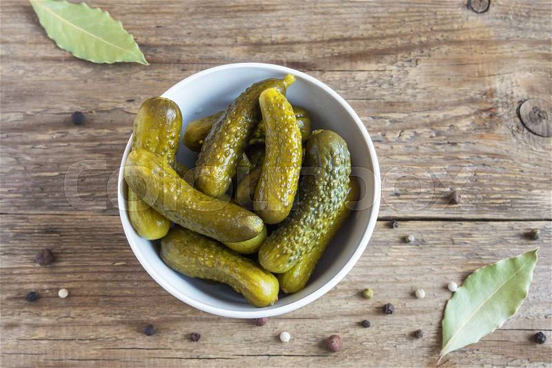 Pickles. Bowl of pickled gherkins (cucumbers) over rustic wooden background close up, stock photo