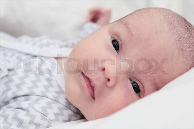 Newborn baby quiet looking, with dark eyes, face closeup, stock photo