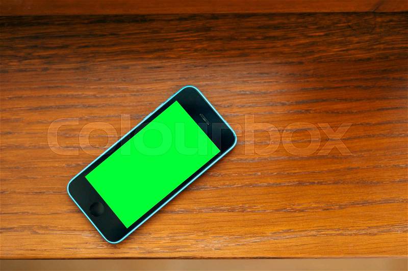 Black and blue phone on the table with a green screen, stock photo