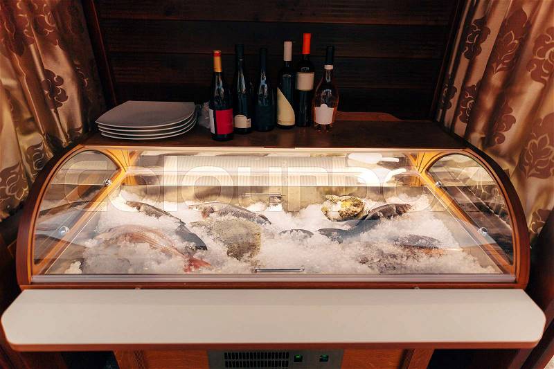 Fresh fish on ice in the fridge. Fish in the restaurant to choose from. Bottles of wine on the fridge, stock photo