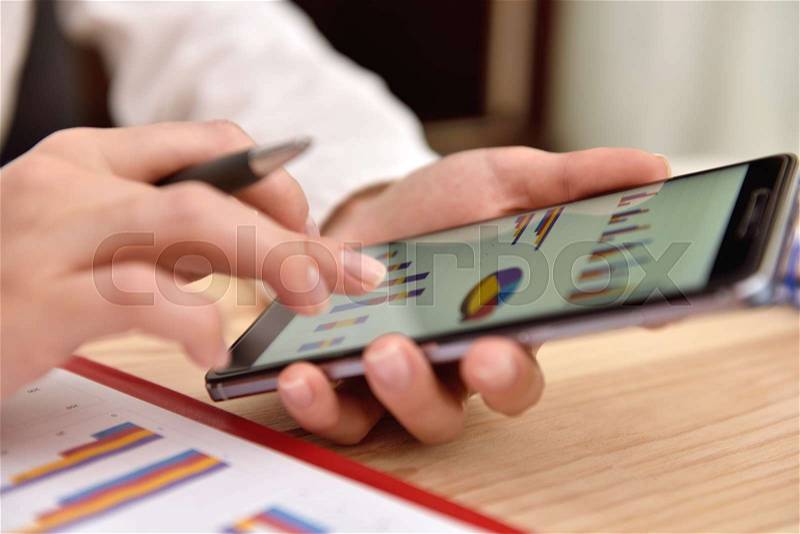 Smart phone with financial data in form of charts and diagrams. Businesswoman analyzing report, stock photo