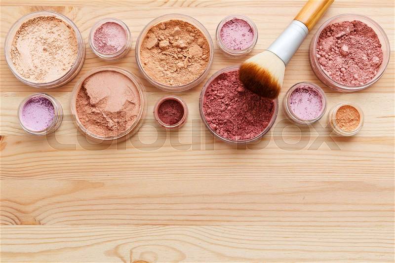 Makeup powder products with foundation blush and brush on wood background, stock photo