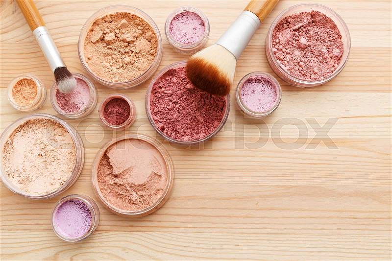 Makeup powder products with brushes on wood background, stock photo