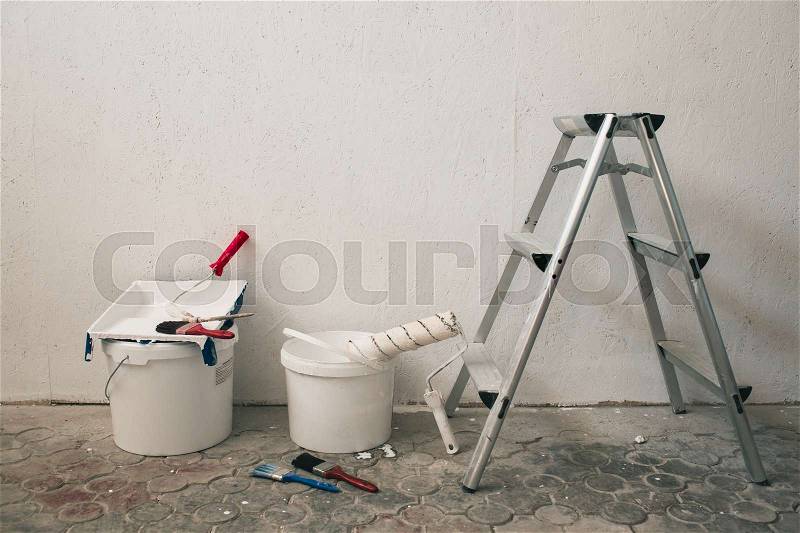 Wall prepared for painting. Brushes, buckets of paint, stairs near the wall, stock photo