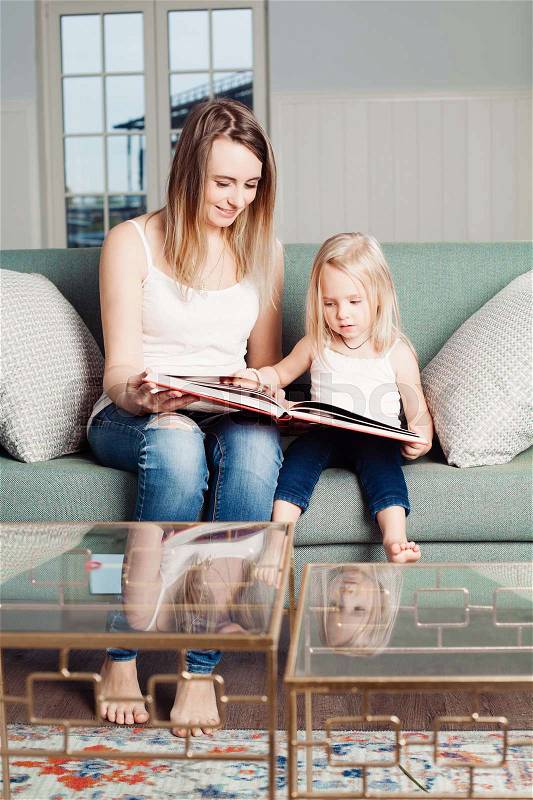 Mothers and Daughter at Home. Mum Reads a Book to her Daughter, stock photo