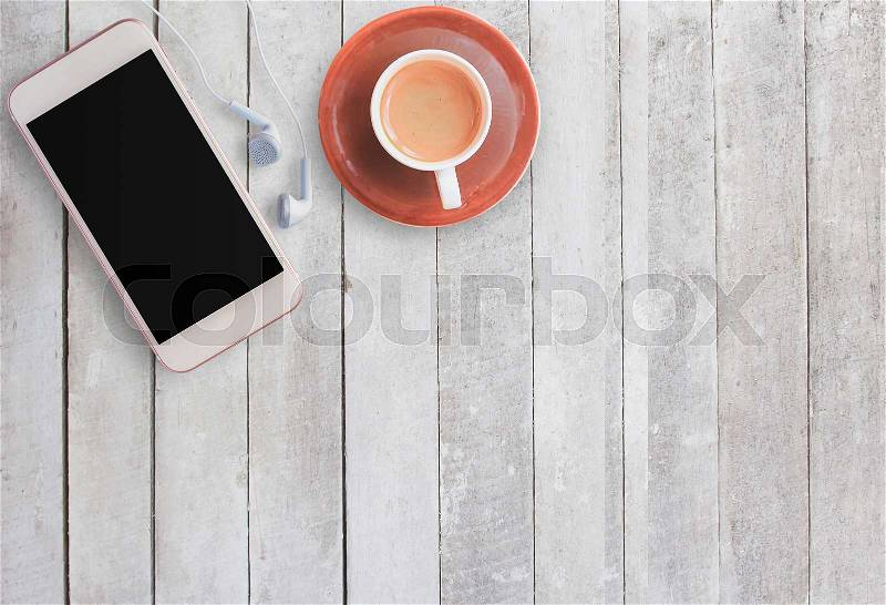 Coffee cup and smart phone with earphone on white wood background. Top view with copy space (selective focus). Office desk table concept, stock photo