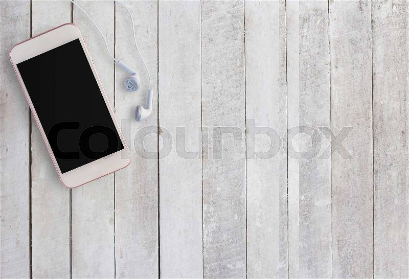 Smart phone and earphone on white wood background. Top view with copy space (selective focus). Office desk table concept, stock photo