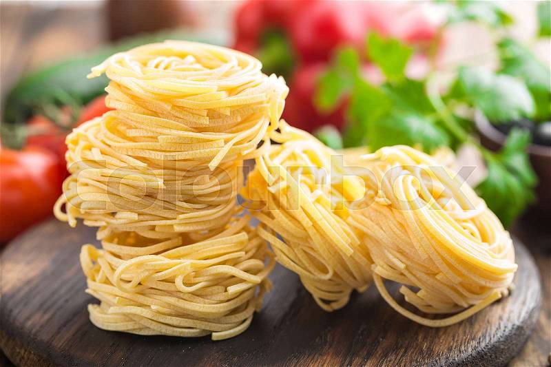 Raw all\'uovo pasta, egg noodles with cooking ingredients on dark wooden rustic background, traditional italian cuisine, stock photo