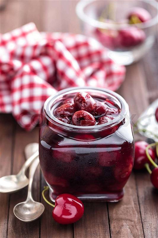 Berries cherry with syrup in a glass jar. Canned fruit, stock photo
