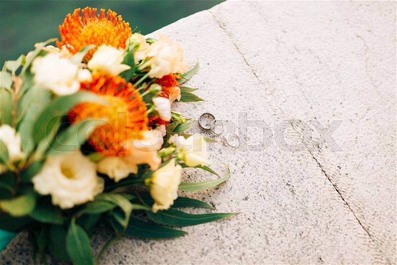 Wedding rings and bunch of Proteus, Verdure Italian , Lisianthus on the stone steps. Wedding jewelry, stock photo