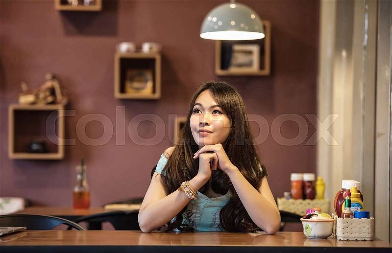 Thoughtful woman sitting alone in restaurant, stock photo