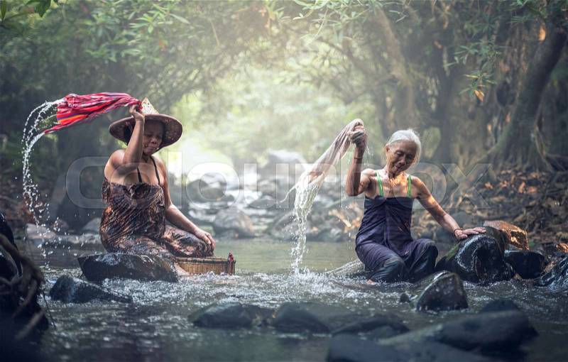 Asian old women washing clothes at the creek, stock photo