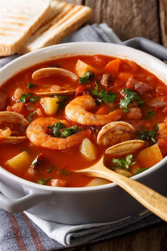 Manhattan clam chowder soup with shellfish and bacon close-up on a in a panon the table. Vertical , stock photo