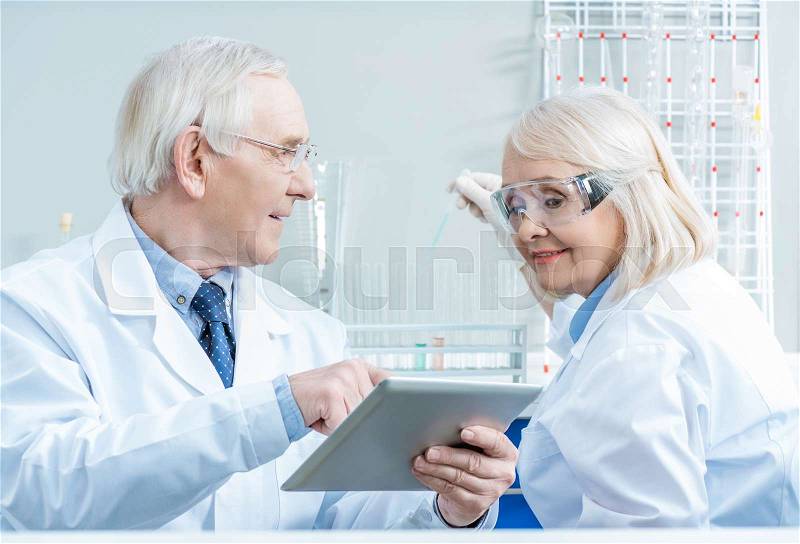 Senior couple of scientists working with digital tablet in lab, stock photo