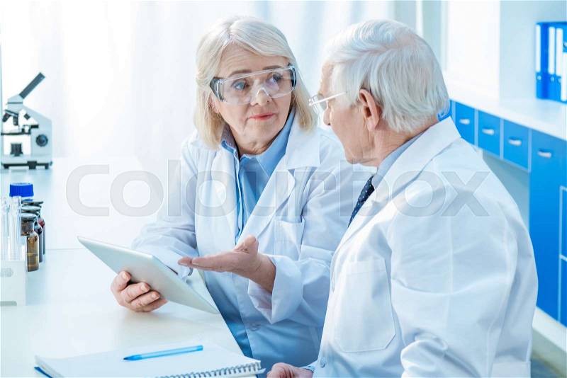 Senior couple of scientists with digital tablet in laboratory, stock photo