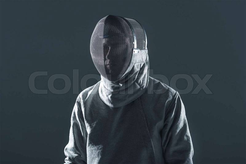 Portrait of professional fencer in fencing mask standing on grey, stock photo