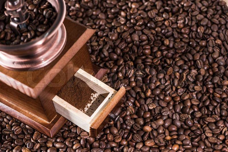 Elevated view of coffee mill with ground coffee on coffee beans, stock photo